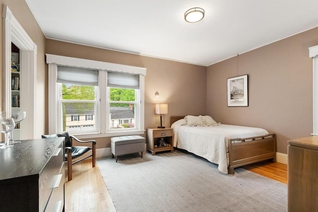 bedroom featuring light wood-type flooring, baseboards, and ornamental molding