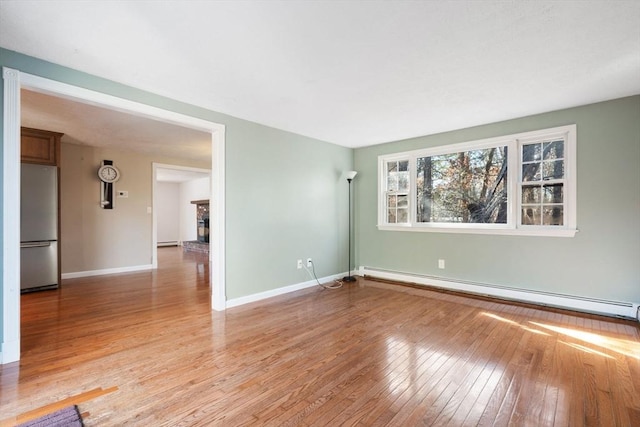 spare room with baseboard heating and light wood-type flooring