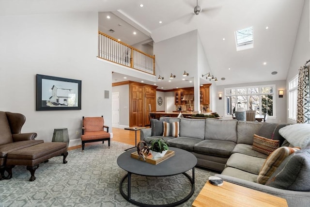 living room featuring a skylight, baseboards, a high ceiling, light wood-type flooring, and recessed lighting