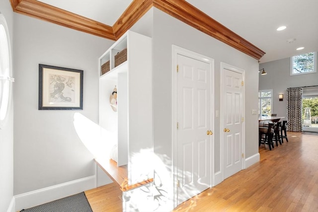 hallway with recessed lighting, crown molding, baseboards, and wood finished floors