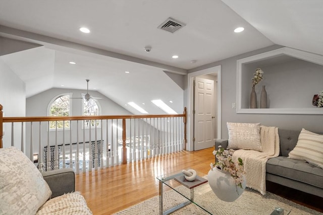 living area featuring lofted ceiling, wood finished floors, visible vents, and a ceiling fan