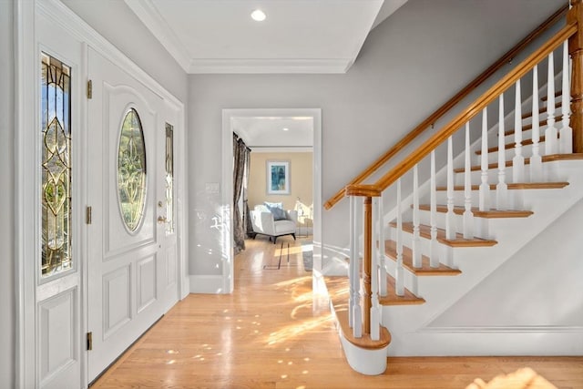 foyer entrance featuring stairway, baseboards, crown molding, and wood finished floors