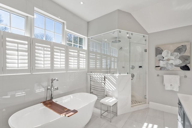 full bath with a stall shower, lofted ceiling, tile patterned floors, vanity, and a freestanding tub