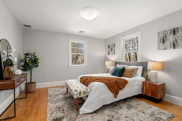 bedroom with baseboards, visible vents, and wood finished floors