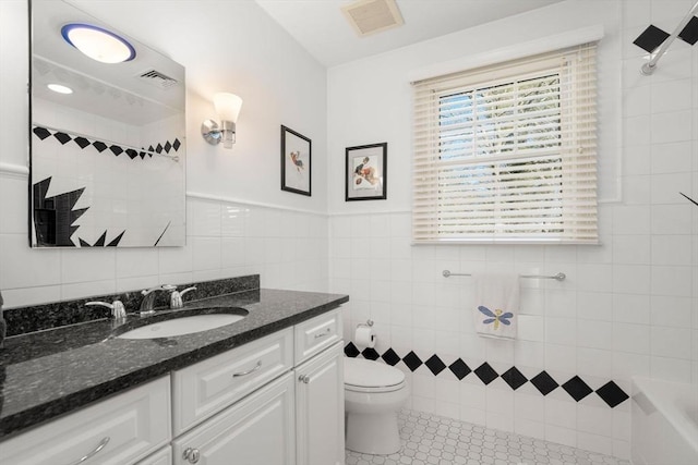 full bath with tile walls, visible vents, toilet, vanity, and tile patterned flooring