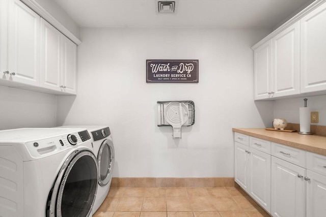 washroom featuring washing machine and clothes dryer, light tile patterned floors, cabinet space, visible vents, and baseboards