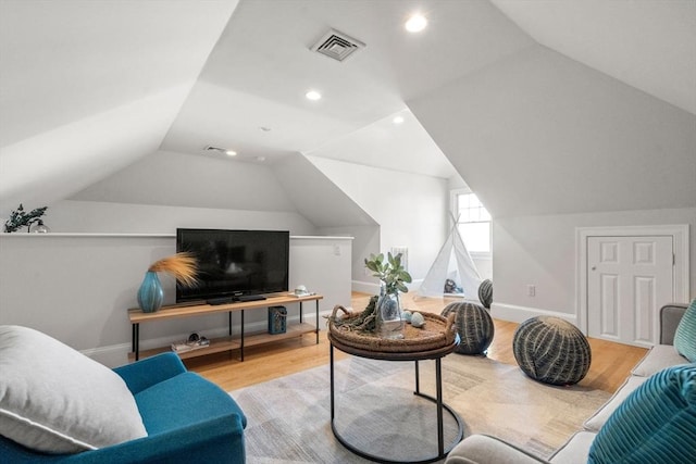 living room with lofted ceiling, visible vents, baseboards, and wood finished floors