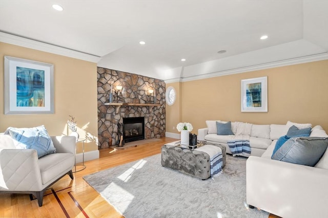 living room with a stone fireplace, ornamental molding, wood finished floors, and recessed lighting