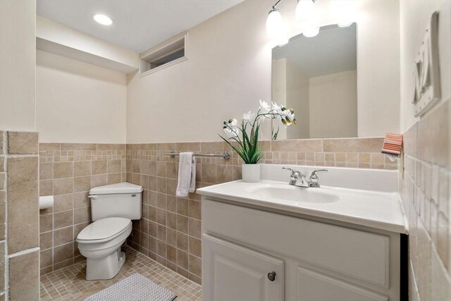 bathroom featuring toilet, vanity, tile walls, wainscoting, and tile patterned floors