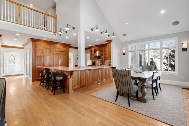 dining room with high vaulted ceiling, light wood-style flooring, baseboards, and ornamental molding