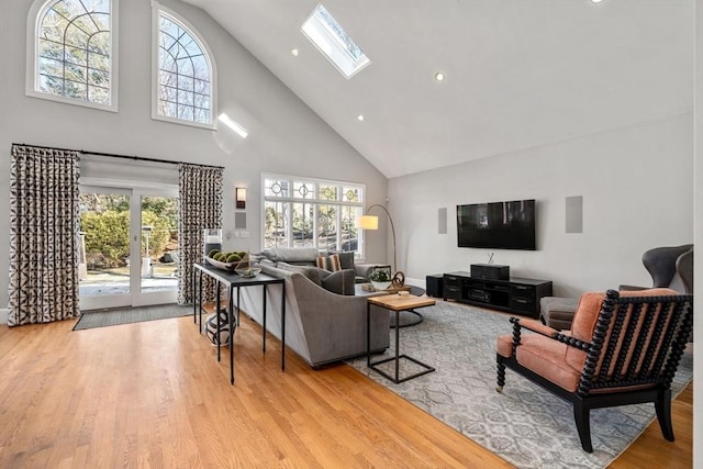 living area with high vaulted ceiling, a skylight, wood finished floors, and recessed lighting