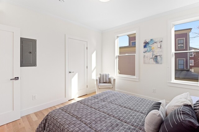 bedroom featuring light wood-type flooring, crown molding, and electric panel