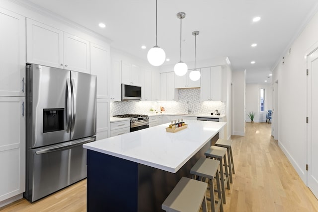 kitchen featuring a kitchen island, white cabinets, ornamental molding, and appliances with stainless steel finishes