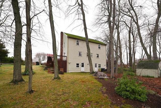 back of house with a wooden deck, a lawn, and a chimney