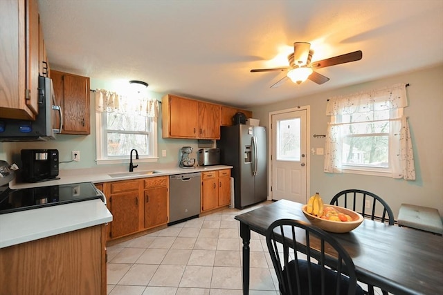 kitchen with appliances with stainless steel finishes, a sink, healthy amount of natural light, and light countertops