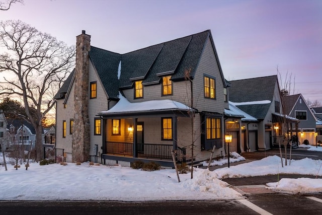 view of front of house featuring a porch, a chimney, and a shingled roof