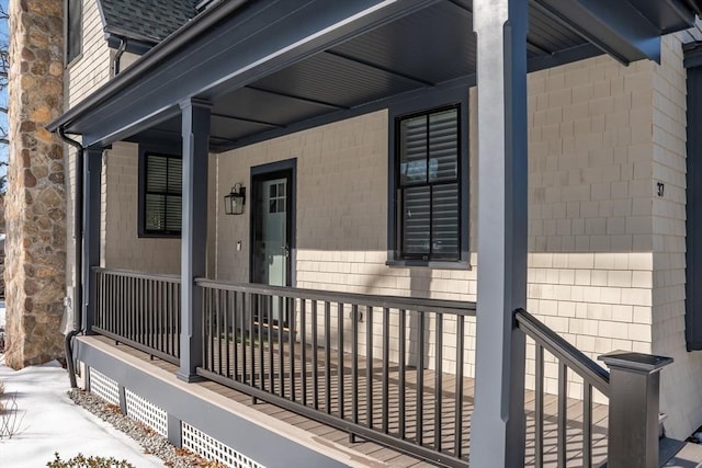 entrance to property featuring covered porch and roof with shingles