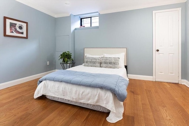 bedroom featuring crown molding, baseboards, and wood finished floors