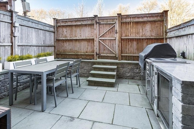 view of patio featuring a gate, an outdoor kitchen, outdoor dining space, and fence