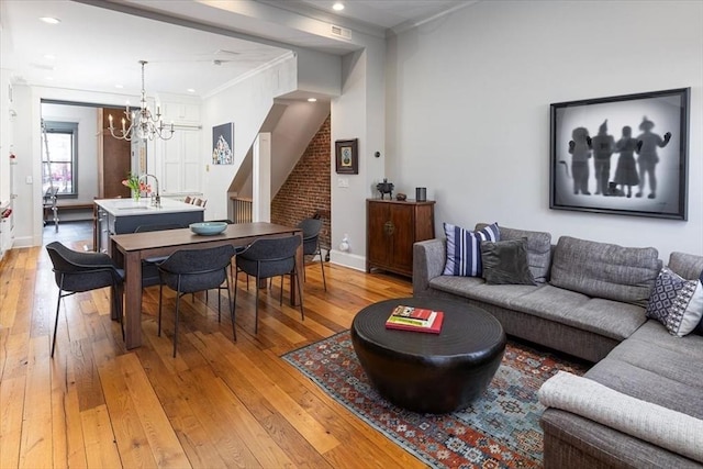 living area with light wood finished floors, recessed lighting, stairs, crown molding, and a notable chandelier