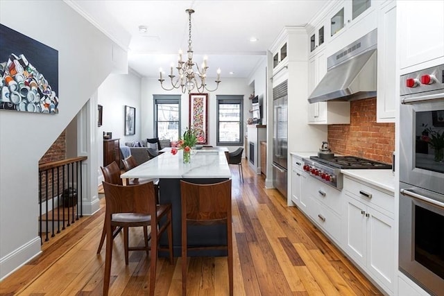 dining room featuring a chandelier, light wood-style flooring, crown molding, and baseboards