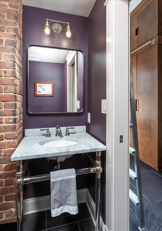 bathroom with tile patterned flooring, brick wall, baseboards, and a sink