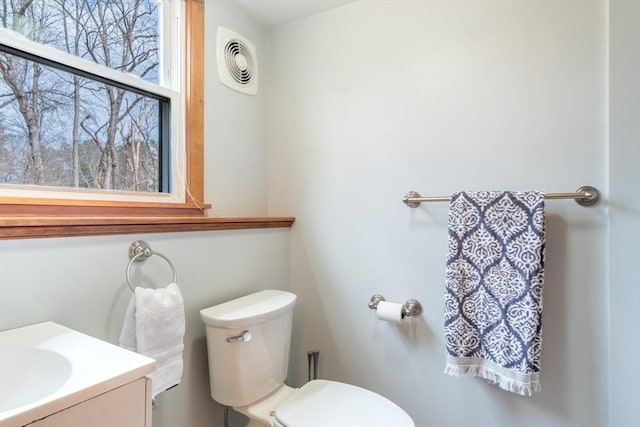 half bath featuring vanity, toilet, and visible vents