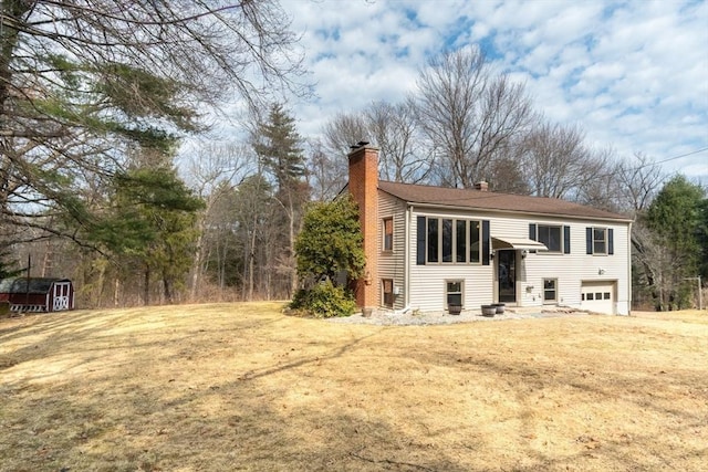 back of property featuring a storage unit, an outbuilding, entry steps, a garage, and a chimney