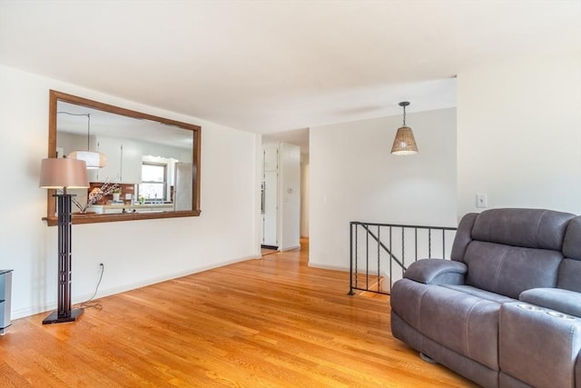 living area featuring an upstairs landing, baseboards, and light wood-style floors