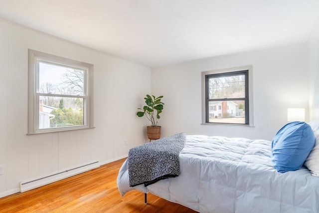 bedroom with a baseboard heating unit and wood finished floors