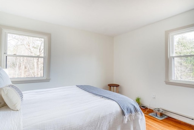 bedroom featuring baseboard heating and wood finished floors