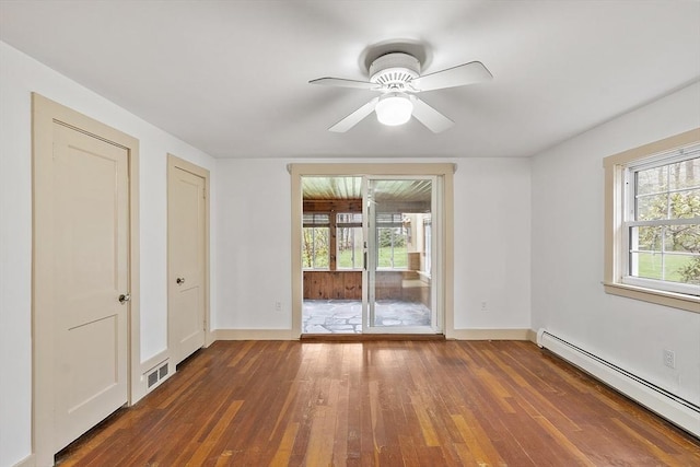 spare room with a healthy amount of sunlight, baseboard heating, visible vents, and hardwood / wood-style flooring