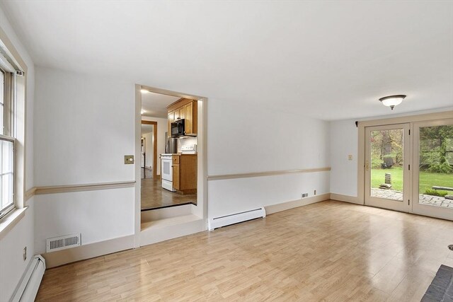 unfurnished room with a healthy amount of sunlight, baseboard heating, and visible vents