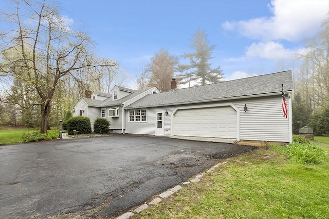 view of front of house with a chimney, a shingled roof, aphalt driveway, and an attached garage