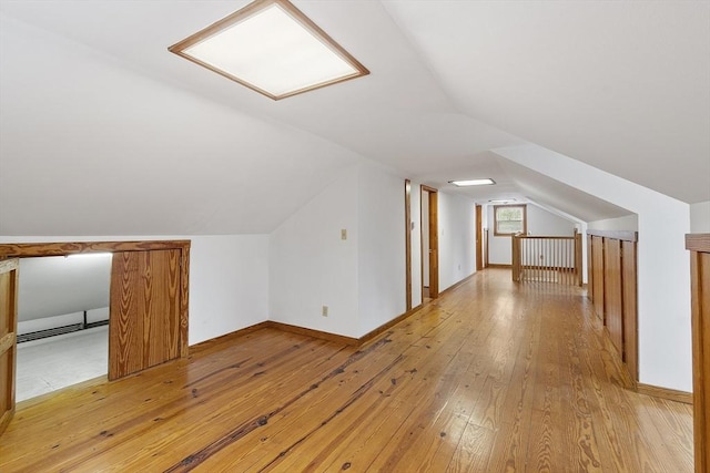 additional living space with lofted ceiling, baseboards, and light wood-style flooring