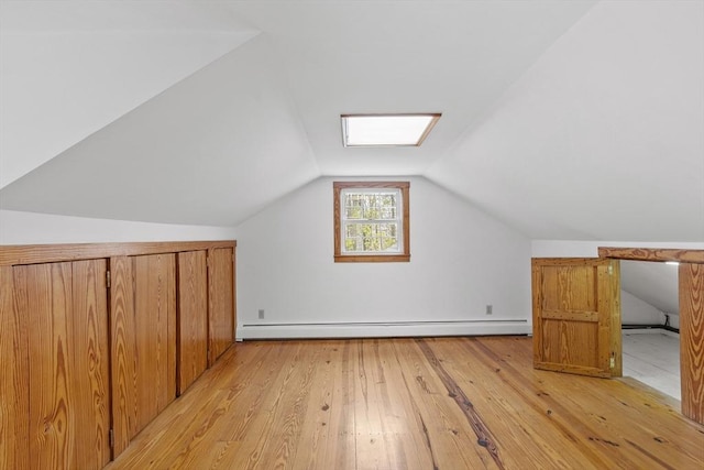 additional living space with vaulted ceiling, light wood-type flooring, and a baseboard heating unit