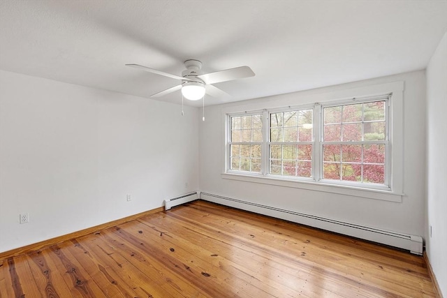 unfurnished room featuring ceiling fan, a wealth of natural light, hardwood / wood-style floors, and a baseboard heating unit