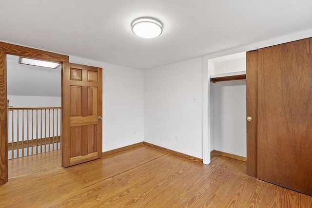 unfurnished bedroom featuring baseboards, a closet, and light wood-type flooring