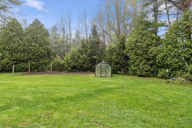 view of yard featuring a greenhouse and an outbuilding