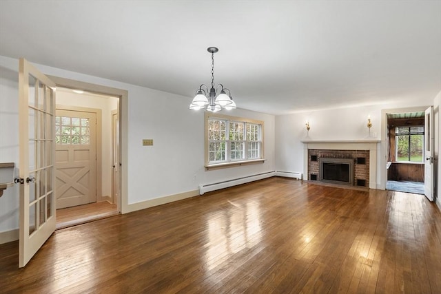 unfurnished living room featuring a chandelier, hardwood / wood-style floors, a healthy amount of sunlight, and a baseboard heating unit