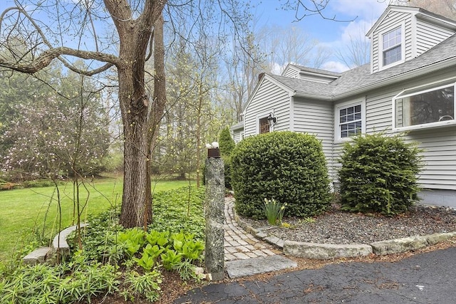 view of property exterior with a shingled roof and a lawn