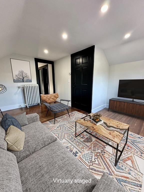 living area featuring baseboards, radiator, wood finished floors, and vaulted ceiling