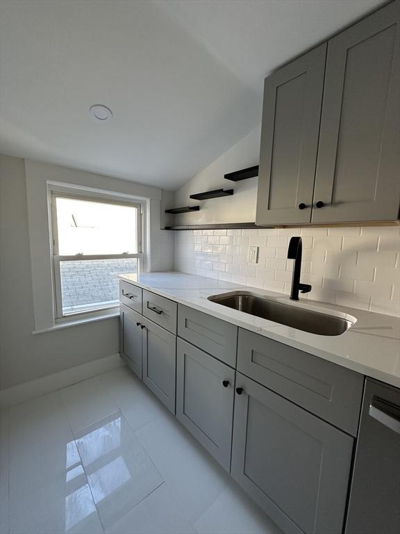 kitchen with a sink, open shelves, dishwasher, and gray cabinetry