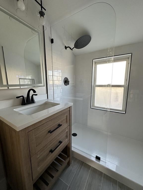 full bathroom featuring a walk in shower, vanity, and wood finish floors