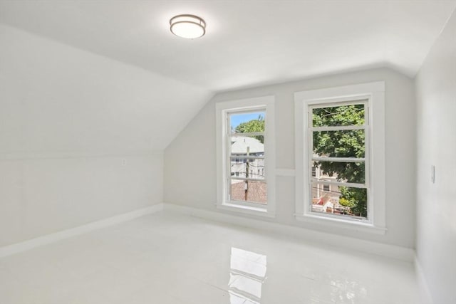 additional living space featuring baseboards and vaulted ceiling