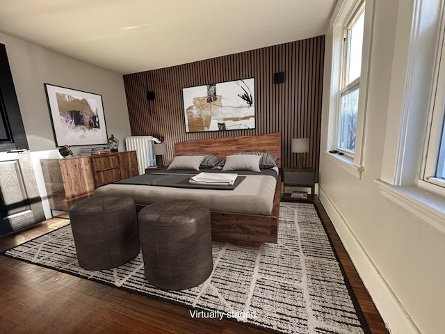 bedroom featuring an accent wall, multiple windows, wood finished floors, and baseboards