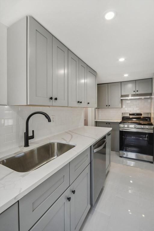 kitchen with a sink, appliances with stainless steel finishes, gray cabinets, and under cabinet range hood