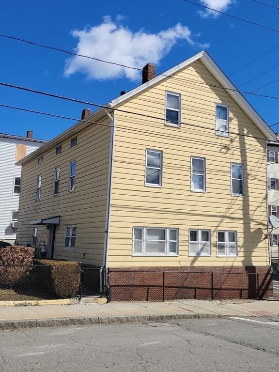 view of side of home with a fenced front yard and a chimney