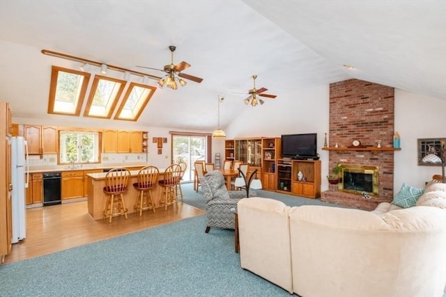 living room featuring vaulted ceiling, ceiling fan, a fireplace, and a wealth of natural light