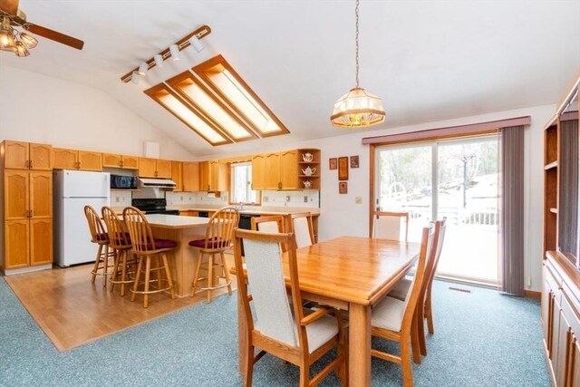 dining area with lofted ceiling, visible vents, light carpet, ceiling fan, and track lighting